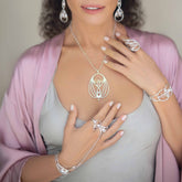 A woman models the Kaora Sandara Jewelry Silver Hand Chain Transition Gift, featuring intricate silverwork with rose quartz sphere gemstones that evoke spiritual love and serenity, her hands gracefully posed to highlight the accessory.