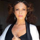 A woman with curly hair wears the Quantum Shift NEW Pendant by Kaora Sandara Jewelry, crafted in sterling silver with crystal gemstones. She pairs it with a black top and white shawl, posing confidently against a dark background.