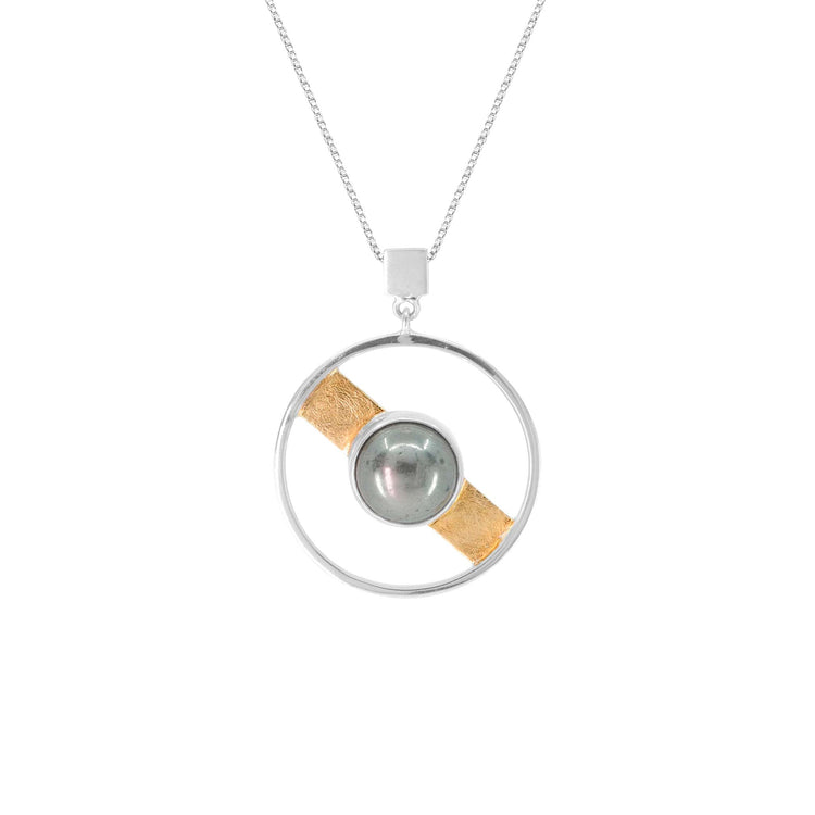 The Animus Pendant by Kaora Sandara Jewelry features a sterling silver circle, a central pyrite sphere, and a diagonal gold-plated band—celebrating masculine qualities in elegant jewelry.