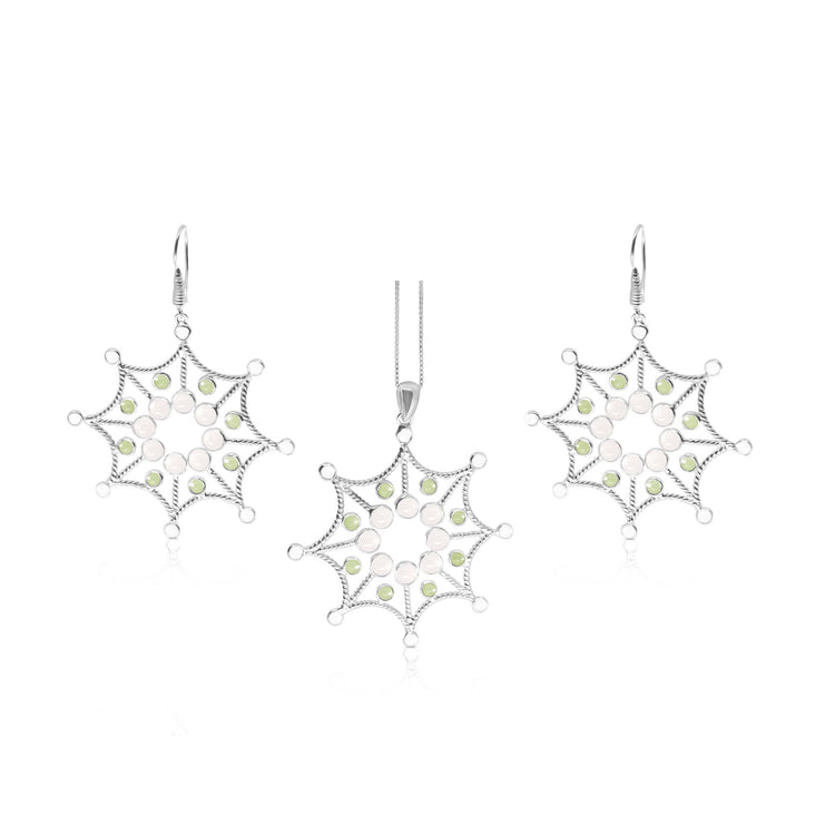 The Freedom from the Ego Pendant set by Kaora Sandara Jewelry features a sterling silver necklace and earrings with snowflake-shaped pendants, adorned with rose quartz and peridot crystals.