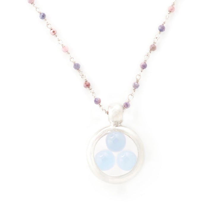 The Silver Pendant Crystal Peace necklace by Kaora Sandara Jewelry features a sterling silver chain with small pink and purple beads, a circular pendant, and three light blue chalcedony sphere gemstones. Shown on a plain white background.