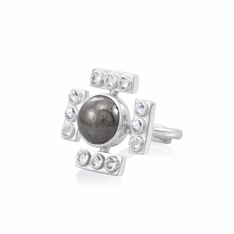 The Confidence Ring by Kaora Sandara Jewelry features sterling silver with a central round pyrite stone, accented by four rectangular sections each set with three crystals, creating a bold, cross-inspired design.